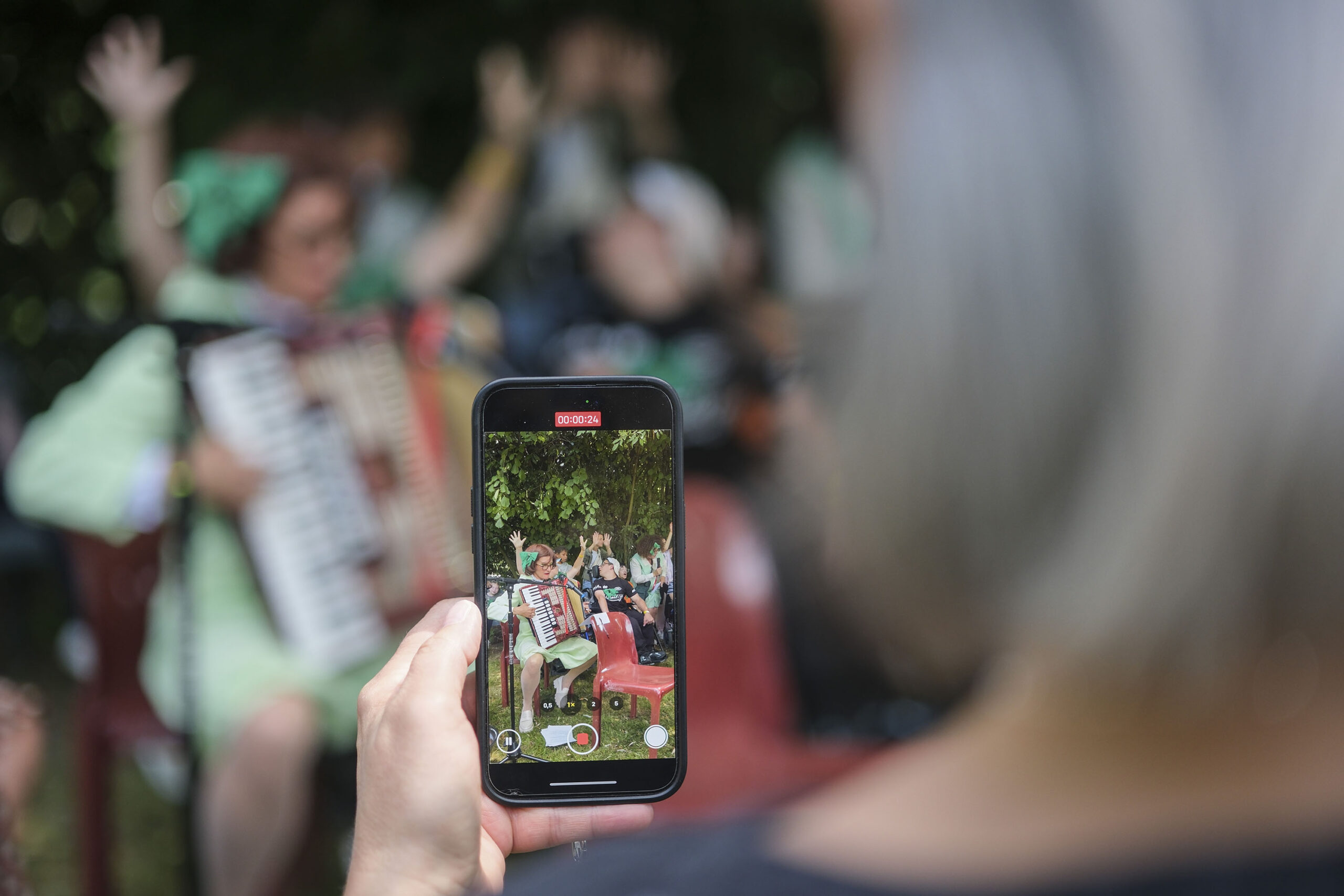 Cie ON-OFF-Plaines Sante-6 Une participante filme l’activité avec son smartphone, tandis que l’artiste Cécile Thircuir joue de l’accordéon, entourée de participants réjouis derrière et autour d’elle.